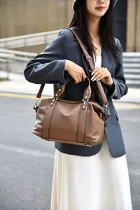 Detail of brown litchi pattern Boston bag with gold rivets and adjustable shoulder strap