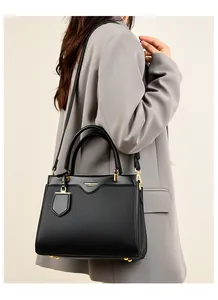 Close-up of black lychee texture leather handbag with gold metal feet and logo plate