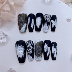 Macro shot of 10pcs matte black press-on nails with white embossed rose floral patterns