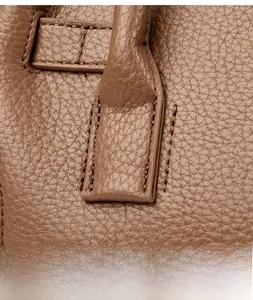 Gros plan détaillé du cuir grainé marron et des coutures précises sur un sac à main de luxe