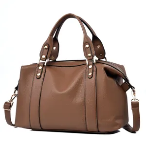 Detail view of brown pebbled leather texture and gold hardware on a Boston handbag