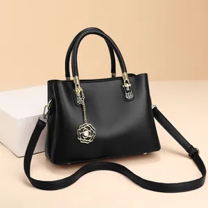 Schwarze Handtasche aus Litschi-Leder mit Kamelien-Anhänger und goldenen Details