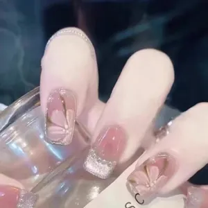 Dettaglio di unghie finte rosa con glitter argento e delicati motivi floreali dipinti