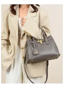 Sac cabas gris en cuir grainé avec détails dorés porté par un mannequin chic