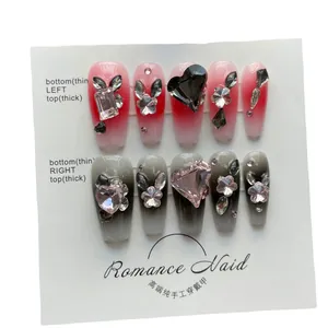 Set di unghie finte fatte a mano con sfumature rosa e nere e ciondoli a cuore in strass
