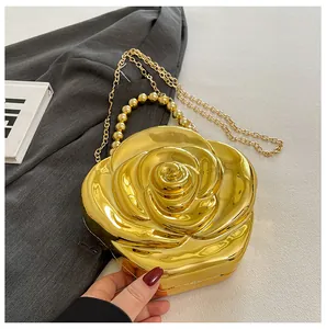 Close-up of golden 3D rose flower evening clutch bag with beaded handle and chain