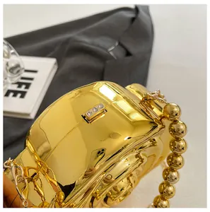 Detail of gold mirror acrylic clutch with crystal clasp and pearl bead handle