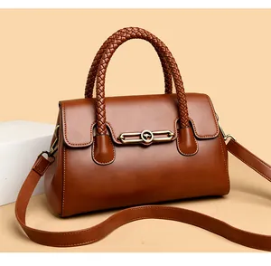 Detail of brown leather handbag featuring woven handle and kangaroo metal clasp
