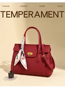 Detail of red lychee grain leather tote bag with gold buckle and decorative silk scarf