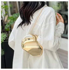 Back view of model wearing a glossy gold irregular spherical clutch bag with chain strap