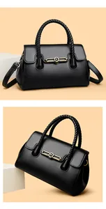 Detail of black leather handbag featuring woven handle and gold kangaroo logo buckle