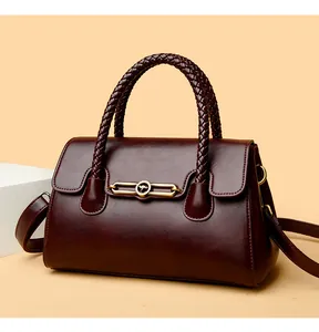 Detailed close-up of dark red leather handbag with woven handles and gold kangaroo buckle
