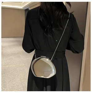 Irregular silver metal crossbody bag with chain strap shown on a black minimalist outfit