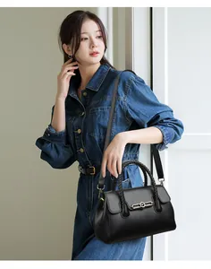 Detail of black leather handbag with woven handle and gold metal ring buckle worn by model