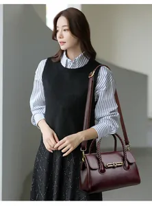 Detail view of burgundy leather handbag with golden kangaroo buckle and woven handle