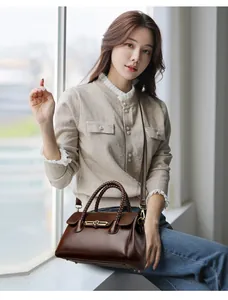Detail of a dark brown leather handbag with woven handles and golden metal clasp