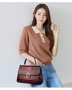 Deep red crocodile embossed bucket bag with metal buckle shown in elegant lifestyle setting