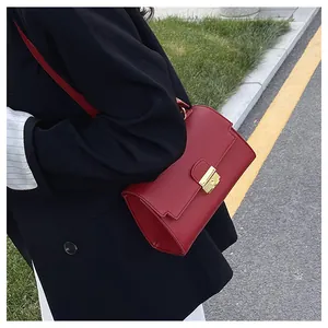 Detail of red pebbled leather handbag with gold buckle styled on a black blazer