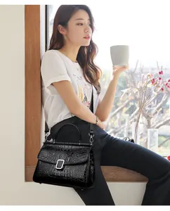 Detail of black crocodile texture handbag with silver buckle in natural window light