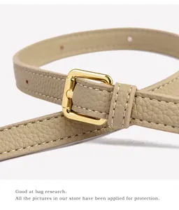Macro shot of beige litchi leather belt featuring a golden square buckle and white stitching