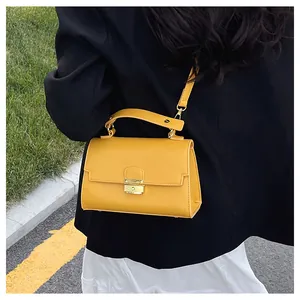 Detail of yellow lychee grain leather bag with gold buckle on a black blazer