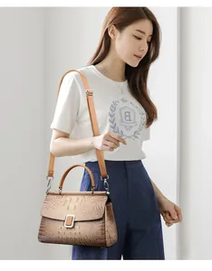 Detail of caramel crocodile pattern bucket bag with silver buckle and adjustable strap