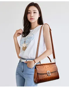 Brown crocodile pattern bucket bag with silver buckle worn as a crossbody handbag