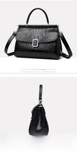 Detail of black crocodile pattern bucket bag featuring a silver square lock and top handle