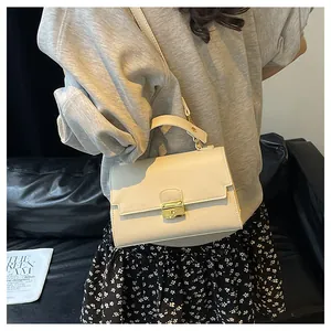 Close-up of cream white crossbody bag with lychee texture and gold metal square lock