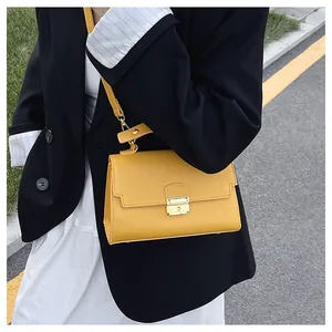 Detail view of yellow lychee grain leather handbag with gold metal lock in outdoor setting