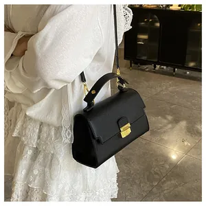 Close-up of black lychee texture leather handbag featuring elegant gold metal hardware buckle