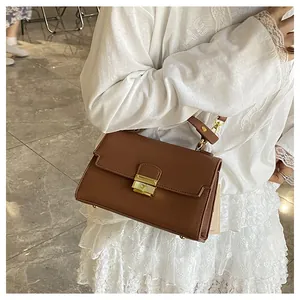 Brown retro PU leather handbag with gold metal clasp shown on a white lace dress model