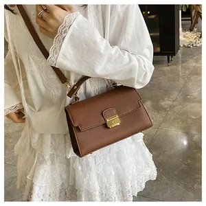 Brown textured leather crossbody bag detail with golden metal lock and top handle