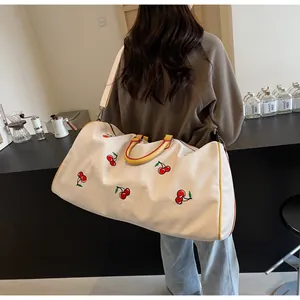 Ricamo dettagliato di ciliegie rosse su una grande borsa da viaggio in tela robusta