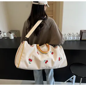 Vista posteriore del modello con borsa da viaggio in tela grande ricamata con ciliegie e manici