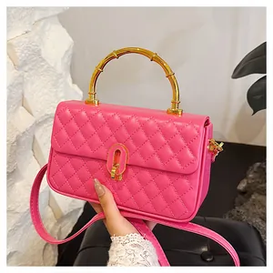 Dettaglio della borsa trapuntata rosso rosa con manico in bambù dorato e tracolla