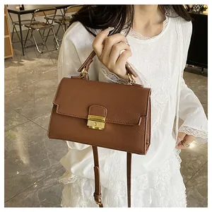 Detail of caramel brown litchi grain handbag featuring gold metal lock and leather strap