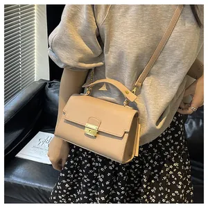 Close-up of beige textured leather handbag with a gold metal lock and shoulder strap