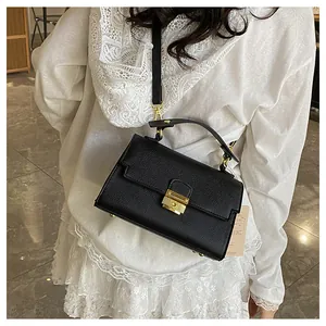 Detail of black lychee grain leather handbag with gold metal hardware and strap