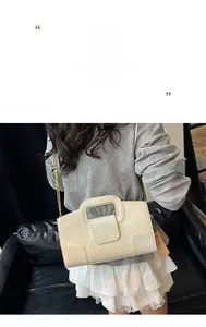 Détail de la texture crocodile crème et chaîne dorée sur un petit sac à main carré
