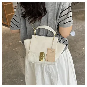 Detail of off-white faux leather crossbody bag featuring crocodile texture and gold lock