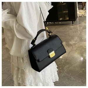Close-up of black lychee-textured handbag featuring gold metal clasp and premium leather