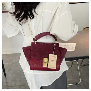 Detail of dark burgundy vintage bag with crocodile pattern and golden metal turn-lock