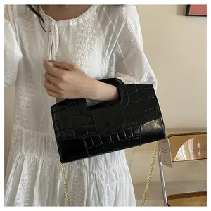 Détail du sac à main noir motif crocodile avec poignée évidée et bandoulière chaîne dorée