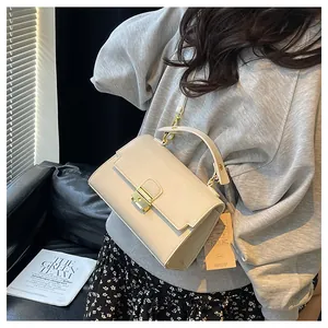 Detail of cream leather handbag showing lychee grain texture and gold metal buckle