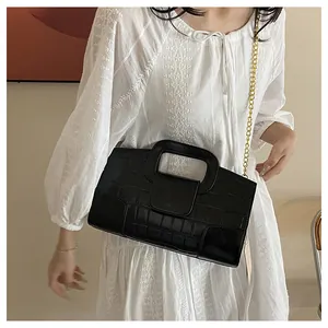 Détail de la texture crocodile noire et chaîne dorée sur un sac à main élégant
