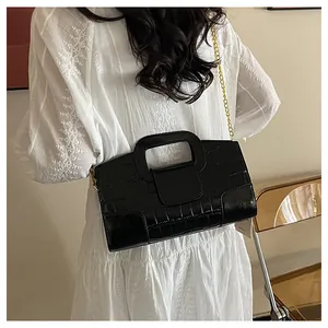 Détail du sac noir à texture crocodile avec chaîne dorée porté à la taille du mannequin