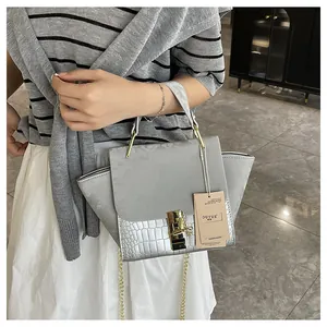 Detail of grey frosted handbag with faux crocodile leather and gold twist lock closure