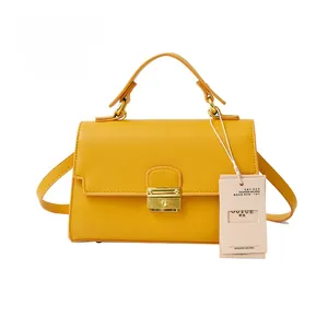 Detail view of yellow lychee leather bag texture with gold metal buckle and strap