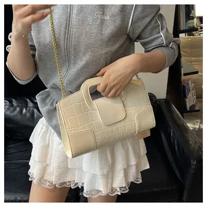 Détail du sac carré gaufré crocodile crème avec bandoulière chaîne dorée porté par mannequin